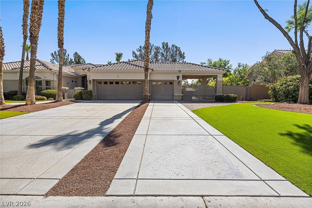 The three-car garage and motor court, with the gated side entry to the rear pool and spa visible to the right.