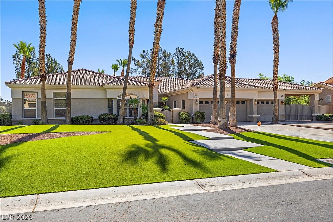 Wide three-quarter view showing the full extent of the front yard, lawn, and palm colonnade.