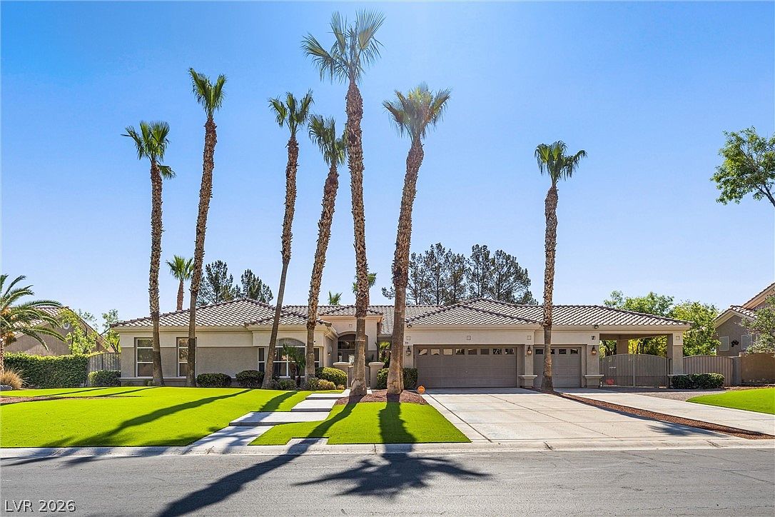 Front elevation of 7310 Red Cinder St, a single-story Mediterranean estate framed by five mature palms against a clear Nevada sky.